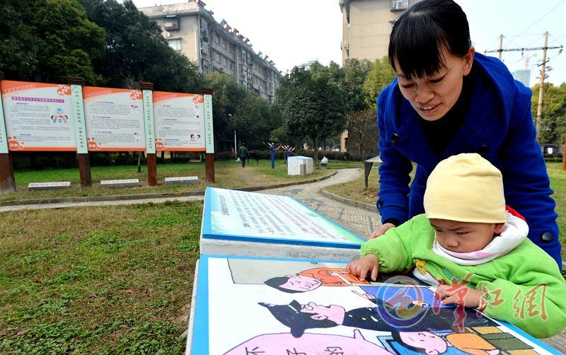 一對母子正在小區新建的法治文化園觀看法律知識漫畫